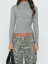 Person wearing a gray long-sleeve top and camouflage pants on a white background